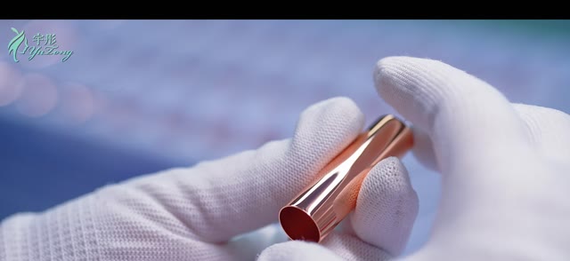 Gloved hands inspecting a metallic brush ferrule