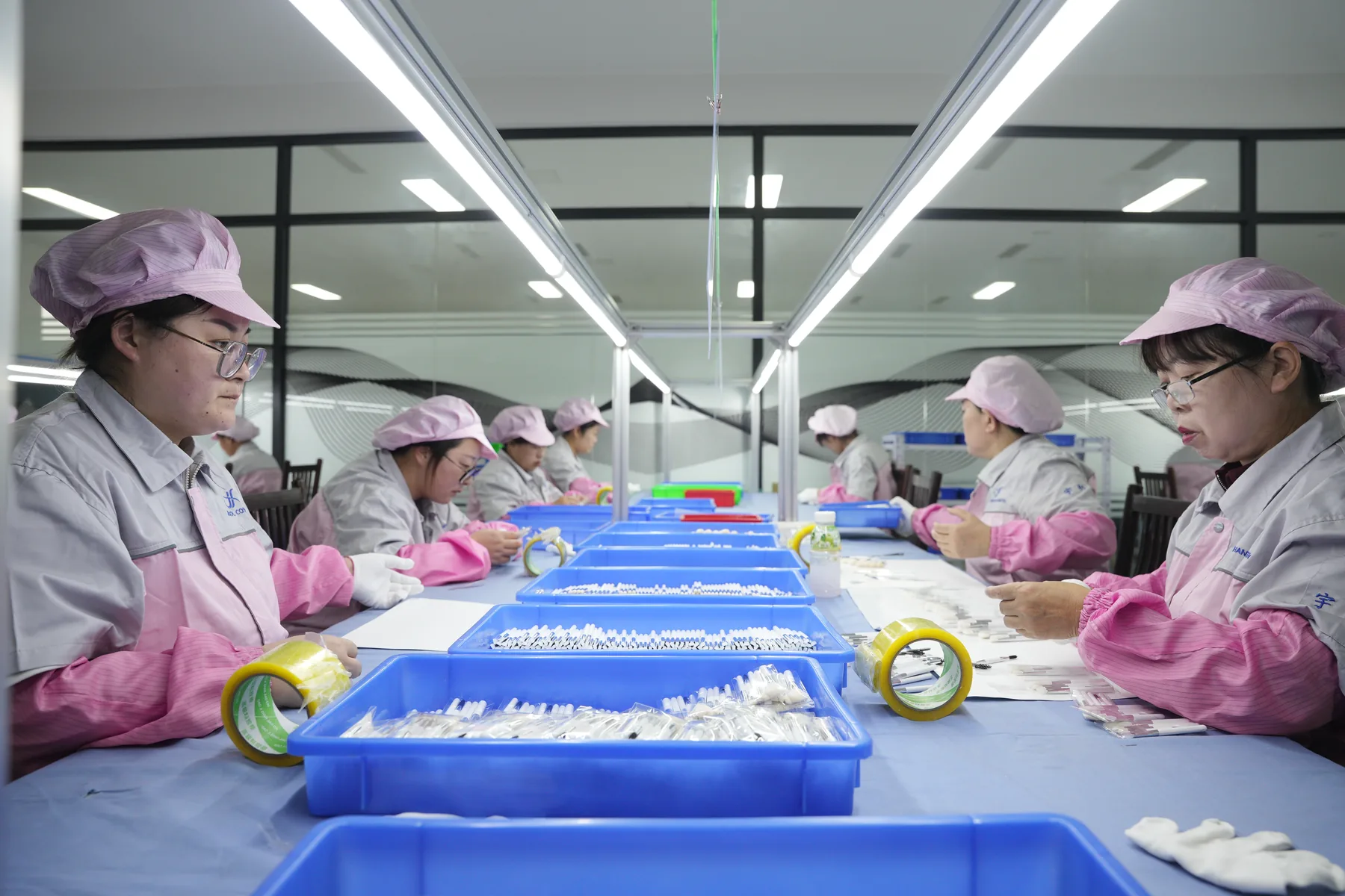 Operators assembling cosmetic brush components at an illuminated production line