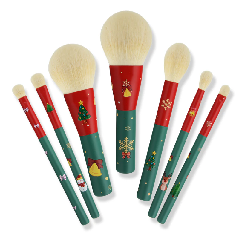 Seven makeup brushes with red and green handles and seasonal motifs